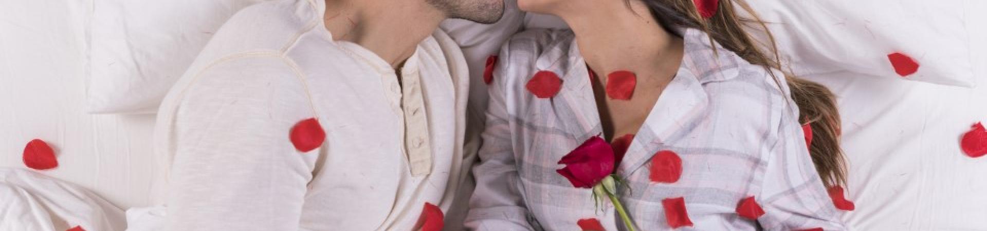 young-couple-kissing-bed-with-rose-petals