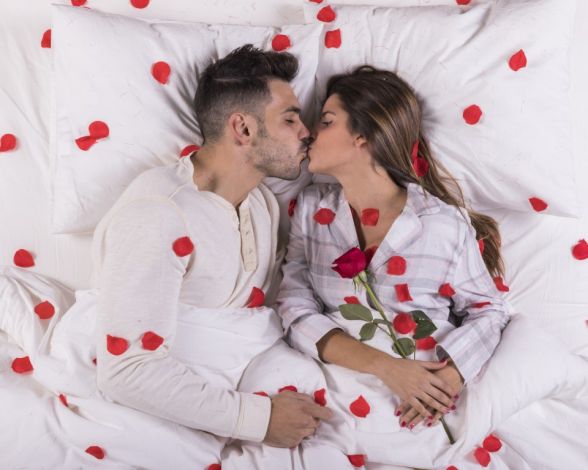 young-couple-kissing-bed-with-rose-petals